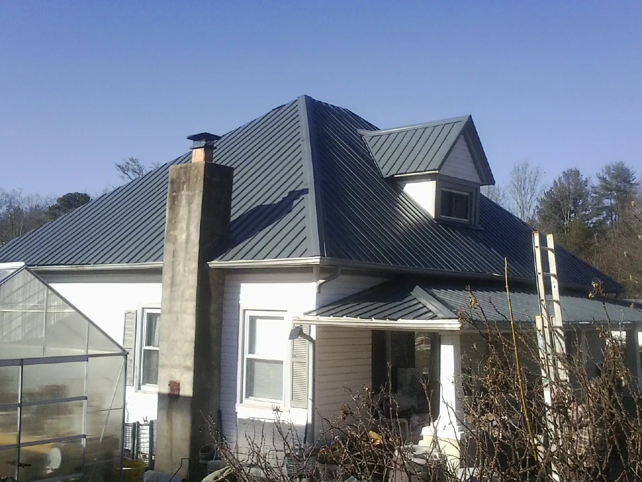 Dark blue standing seam metal roof on a white farmhouse with dormer — Slate & Tile Roof Repair by Roofing Brothers in South Kent