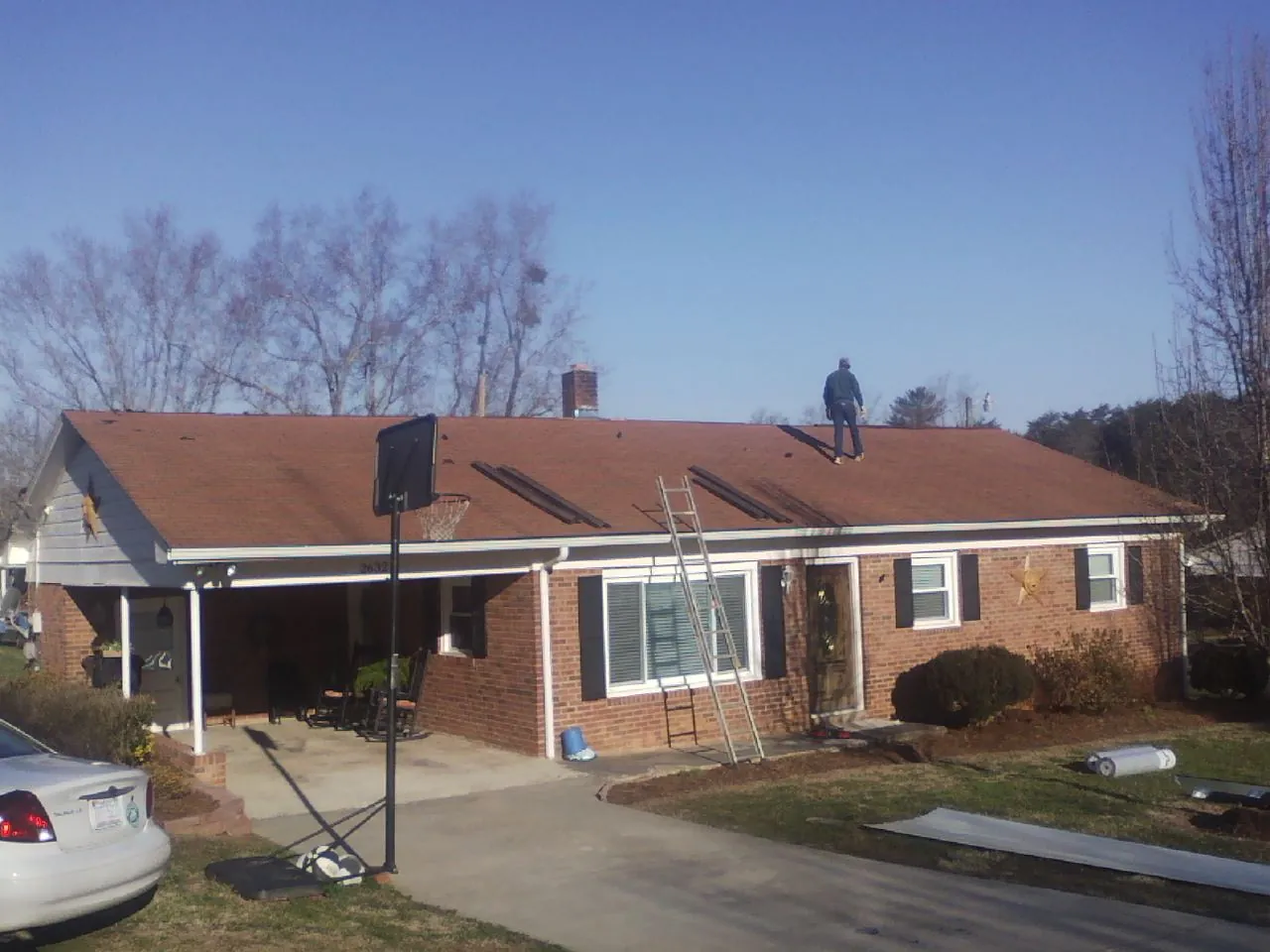 Roofer stripping a shingle roof on a brick ranch before metal panels in South Kent