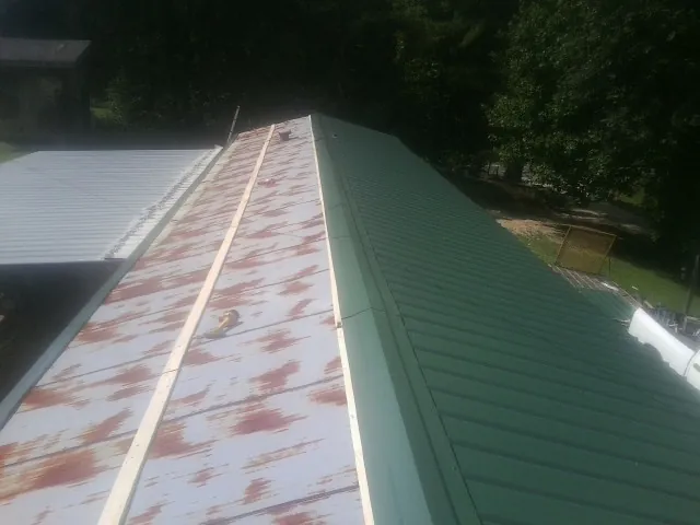 Old rusted panels beside newly installed green metal roofing — Wind Damage Roof Repair by Roofing Brothers in South Kent