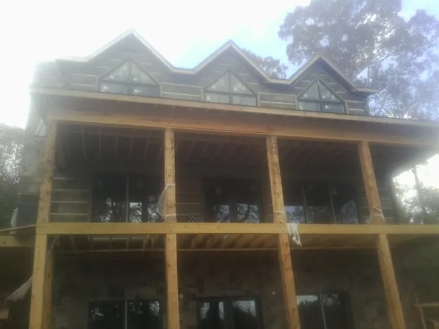 Dormers and porch framing on a large log home under construction — Roof Coating work by our crew in South Kent