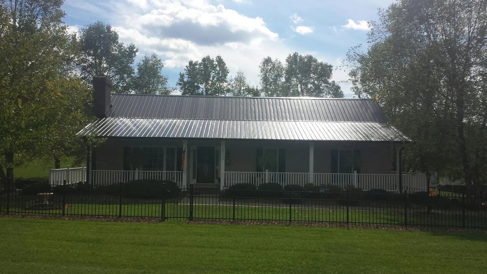 Gray metal roof on a brick ranch with a full width front porch — Gutter Guard Installation work by our crew in South Kent
