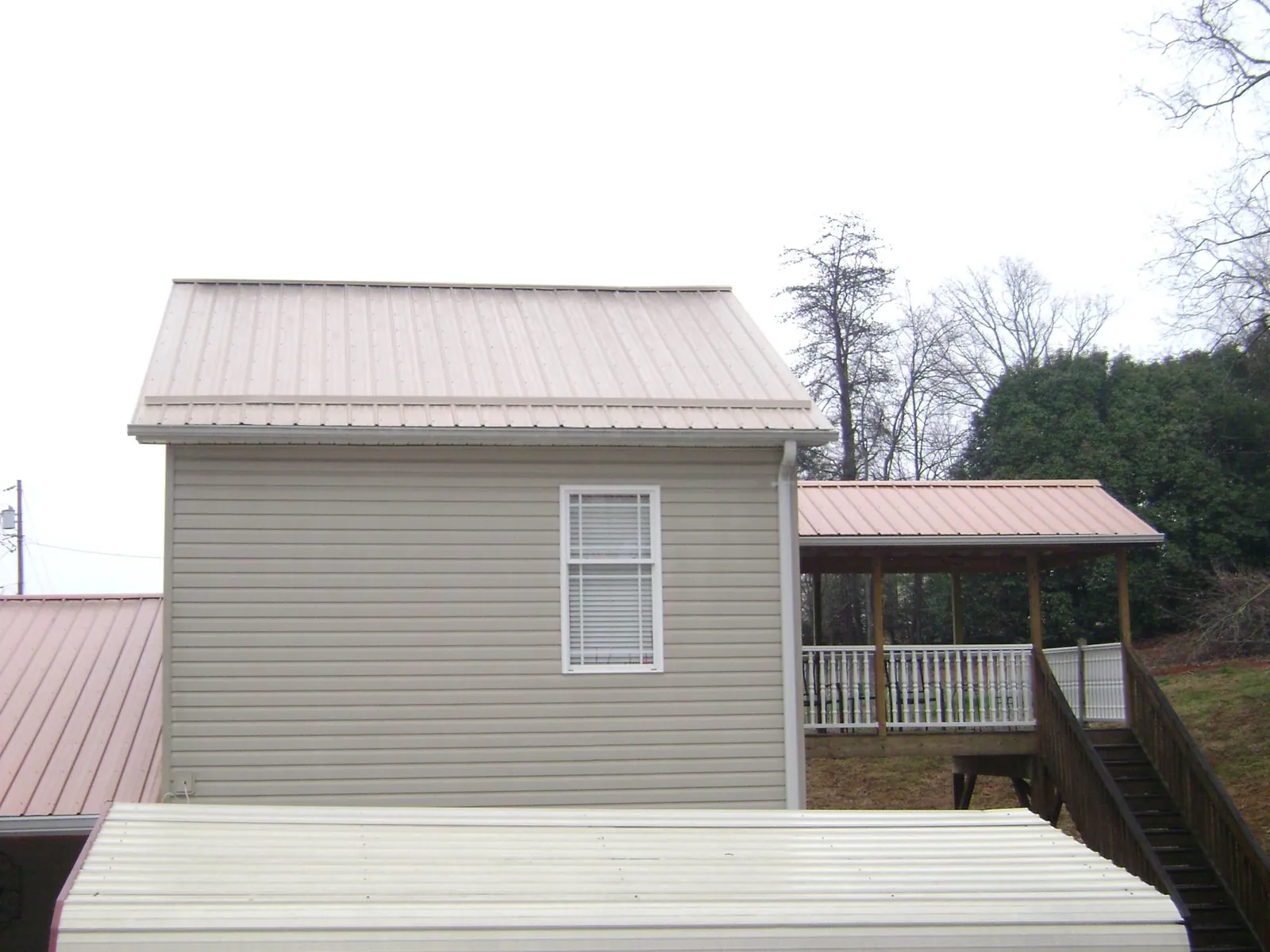 Tan metal roofs on a two story addition and attached porch, from a Roof Replacement job in South Kent