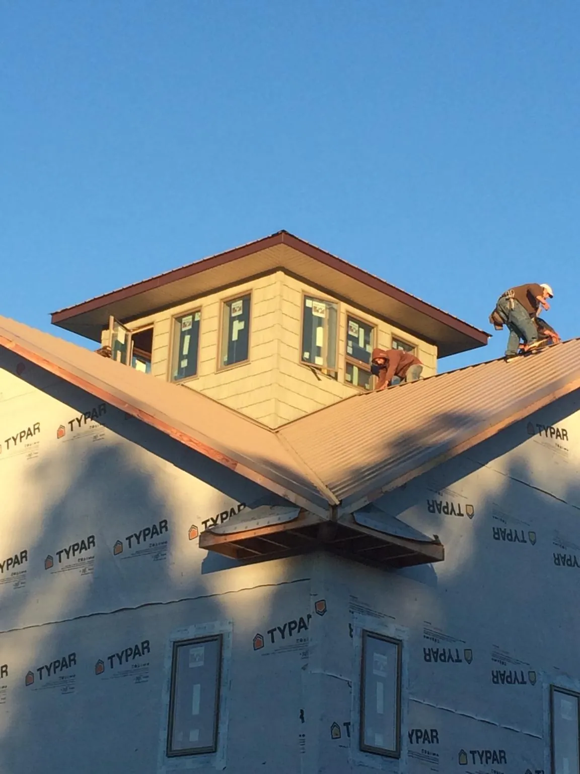Roofers working around a rooftop cupola on a new metal roof at sunset — Roof Waterproofing in South Kent by Roofing Brothers